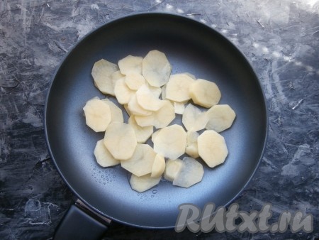 Картофелины очистить и нарезать тонкими кружочками, поместить в сковороду, хорошо разогретую с растительным маслом.