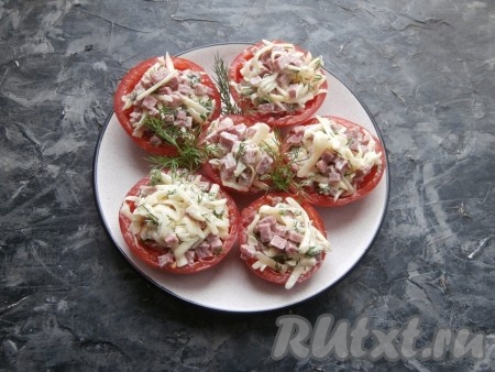 Разместить фаршированные помидоры на тарелке, украсить сверху зеленью.