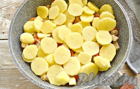 Нарезаем очищенные картошины на кружочки толщиной около 7-9 мм и выкладываем в 1-2 слоя поверх овощей со свининой. Если картошка крупная, нарежьте её полукружочками.
