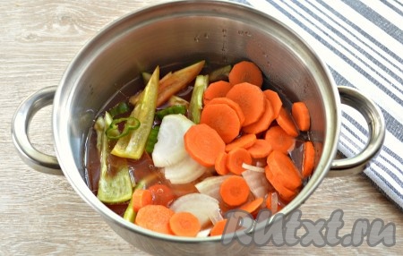 Вливаем в кастрюлю тёплую кипячёную воду, растительное масло, перемешиваем, добавляем нарезанные морковку, болгарский и острый перцы, лук.