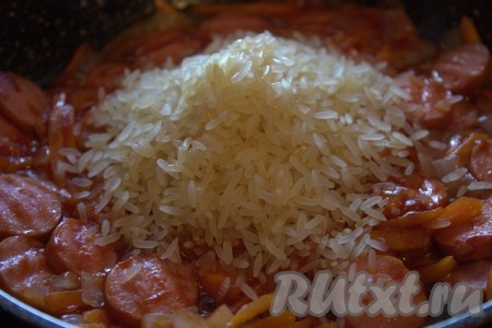 В сковороду к овощам и сосискам выложить рис, перемешать.