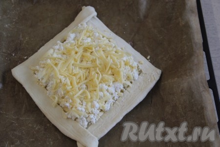 Хачапури переложить на противень, застеленный пергаментом (или тефлоновым ковриком). Выложить начинку из творога и сыра в серединку хачапури (начинка не должна попадать на бортики). Поверх начинки выложить отложенный сыр.