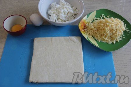 Подготовить продукты для приготовления хачапури из слоёного теста по-аджарски с творогом и сыром. Слоёное тесто разморозить при комнатной температуре. Сыр натереть на тёрке. 
