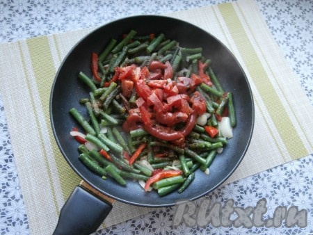 Обжарить фасоль с овощами минуты 3-4, помешивая, а затем добавить чёрный молотый перец, томатный соус, нарезанные кубиками помидоры, соль, специи.