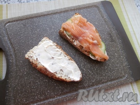 Оба ломтика хлеба смазать сливочным сыром. На один ломоть выложить кружочки огурца и тонко нарезанные кусочки слабосолёного лосося.