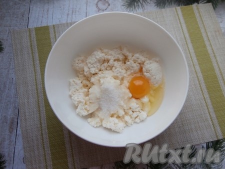 Творог выложить в достаточно объёмную миску, добавить щепотку соли, яйцо, 3 столовые ложки сахара и ванильный сахар.