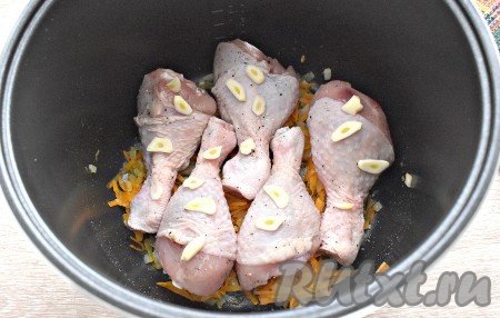 На обжаренные овощи кладём куриные голени, поверх мяса выкладываем очищенные зубчики чеснока, нарезанные на тонкие пластины.