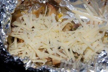 Через 20 минут вынуть из духовки запеченные шампиньоны и картофель. На шампиньоны выложить слой тертого сыра.