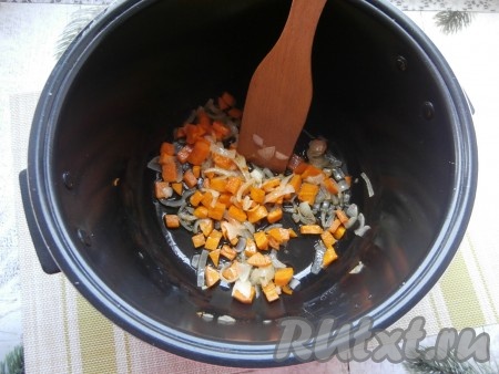 Морковку, чеснок и лук очистить. Влить в чашу мультиварки растительное масло, выложить нарезанный произвольно лук и нарезанную небольшими кубиками морковку. Выставить режим "Жарка" на 20 минут. Помешивая, жарить овощи 10 минут.
