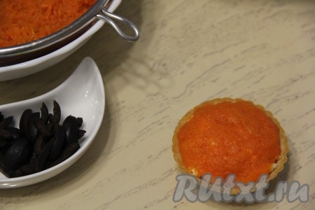 В тарталетки поверх салата выложить натёртую морковь. Чтобы морковка не текла, я предварительно выложила её в сито, чтобы стёк лишний сок.