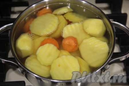 Воду влить в кастрюлю и довести до кипения. Опустить дольки картошки и моркови в воду и варить с момента закипания минут 7.