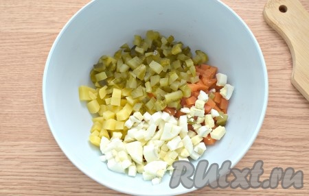 На кубики такого же размера нарезаем маринованные огурцы и яйца, перекладываем к нарезанным морковке и картошке.