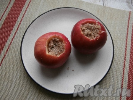 Яблоки разместить на тарелке, подходящей для готовки в микроволновке. Наполнить углубления яблок подготовленной смесью сахара и корицы.