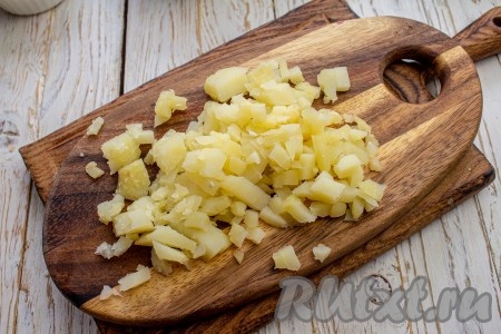 Картофель тоже нарежьте на мелкие кубики и сразу выложите с кастрюлю с нарезанными яйцами.