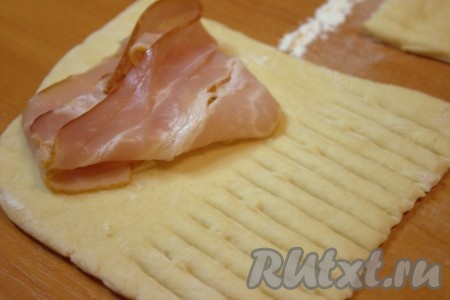 Поверх сыра выложить по одной полоске бекона. Свободную от начинки часть теста нарезать, используя ролик для теста (можно сделать произвольные надрезы, используя нож).