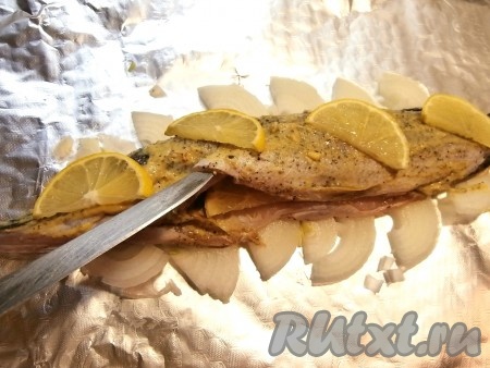 Половину лимона вымыть и нарезать на тонкие полукружочки. В брюшко щуки и поверх рыбки выложить полукружочки лимона. 