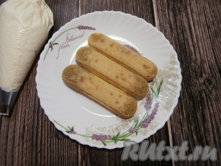Три печенья "Савоярди" смочить в кофе и выложить на тарелку поверх творожных полосок.