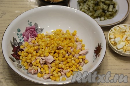 В салатник с копчёной курицей выложить консервированную кукурузу без жидкости.