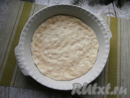 Форму диаметром не менее 26 см (или противень) немного смазать маслом (или застелить пергаментом), выложить тесто, растягивая его руками и придавая круглую форму.