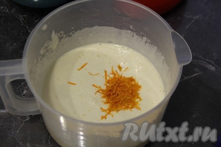 В яичную массу положить апельсиновую цедру и влить растопленное не горячее сливочное масло, перемешать тесто.