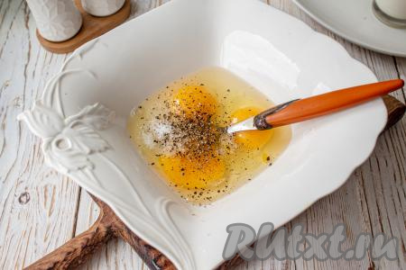 В миску вбейте яйца, добавьте к ним соль и чёрный молотый перец, перемешайте вилкой (или венчиком). 