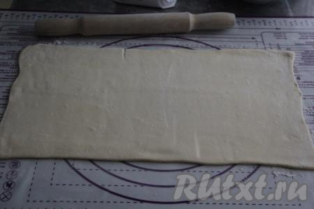 Раскатать размороженное слоёное тесто на присыпанной мукой поверхности до толщины 3-4 мм.