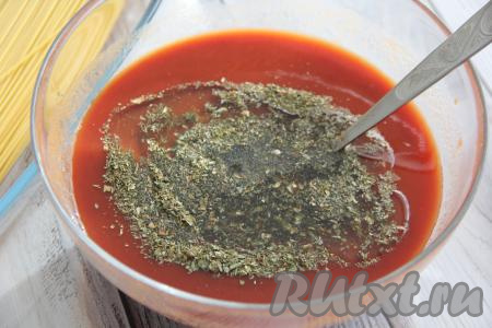 В миску с томатным соусом добавить оливковое масло, пропущенный через пресс чеснок и сушёные травы, перемешать соус.