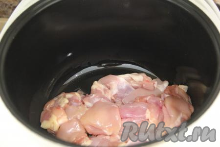 В чашу мультиварки влить масло. Выставить режим "Жарка" и выложить кусочки куриного мяса. 