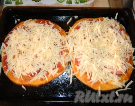 Вынимаем противень с коржами из духовки, выкладываем на них колбасу, затем сыр. Ставим пиццу в духовку на 5 минут.
