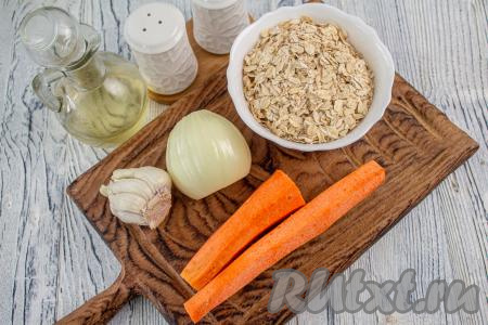 Подготовьте необходимые ингредиенты для приготовления морковно-овсяных котлет. Морковь, половину луковицы и зубчики чеснока очистите.