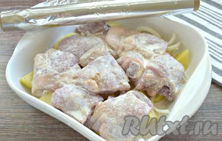 На картошку с луком выкладываем кусочки курицы, сверху поливаем оставшимся сливочным соусом.