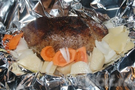 Затем поместить обжаренный кусок мяса на фольгу, вокруг разместить нарезанные овощи.