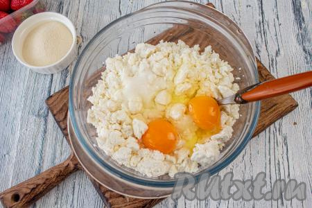 В достаточно объёмную миску выложите творог, добавьте сахар и куриные яйца, перемешайте массу вилкой до однородности.
