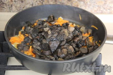 Затем добавить размороженные грибы. Обжарить грибы с овощами в течение 10 минут, периодически помешивая, снять с огня, дать немного остыть. 
