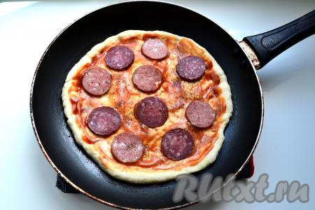 Смазать лепёшку кетчупом и майонезом, выложить нарезанную кружочками колбасу, посыпать пиццу чёрным молотым перцем. Выкладывая начинку, учитывайте, что её нужно равномерно распределить между двумя пиццами.