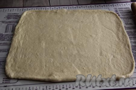 Обмять подошедшее тесто, выложить на поверхность, припылённую мукой (я выложила на силиконовый коврик) и раскатать в прямоугольный пласт толщиной 2-3 миллиметра.