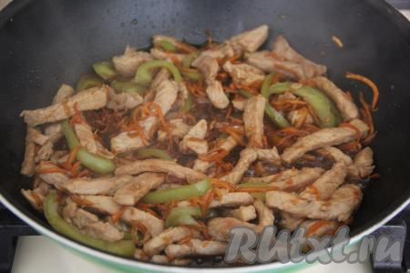 В сковороду со свининой и овощами влить соевый соус, добавить чеснок, нарезанный на тонкие лепестки, перемешать.