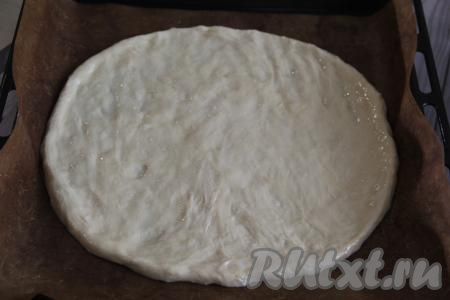 Противень застелить пергаментной бумагой (или ковриком для выпечки), Выложить тесто и руками, смазанными маслом, растянуть тесто в круглую основу диаметром 28 сантиметров.