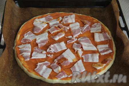 Отдельно смешать майонез и кетчуп, получившейся смесью смазать основу для пиццы. На смазанную основу для пиццы выложить сперва бекон (или колбасные изделия).