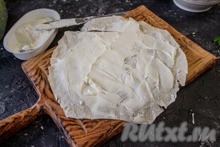 Соберите ролл, для этого круг лаваша смажьте тонким слоем творожного (или любого плавленного) сыра.