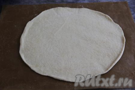 Выложить тесто на пергамент (или на коврик для выпечки), на котором будете выпекать пирог. Раскатать тесто скалкой в круг диаметром, примерно, 28 сантиметров. Переложить бумагу (или коврик) с раскатанным тестом на противень.