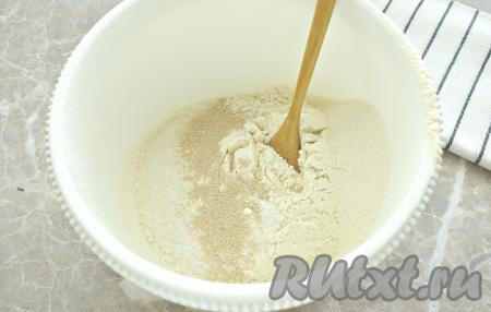 В миску просеиваем пшеничную муку, всыпаем к ней сахар, соль, быстродействующие сухие дрожжи и перемешиваем сыпучие ингредиенты. В центре мучной смеси делаем воронку.