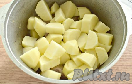 Нарезаем на крупные кубики очищенный картофель и выкладываем в казан поверх свиных рёбрышек.