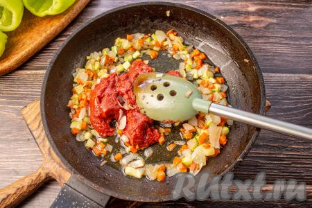 Около 1/3 части обжаренных овощей отложите со сковороду в тарелку (они нам потребуются для начинки). В сковороду с оставшимися овощами положите томатную пасту, перемешайте и, помешивая, обжаривайте пару минут.