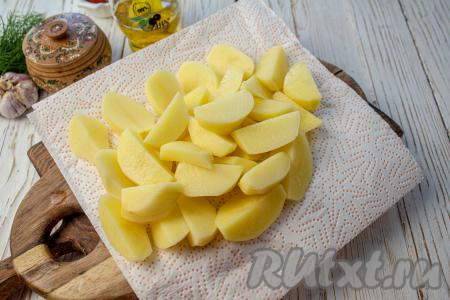 Картофель очистите и промойте. Нарежьте на крупные дольки. Выложите дольки картофеля на бумажное полотенце и обсушите их тщательно.
