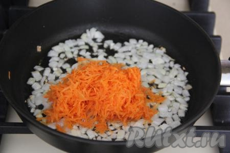 К обжаренному луку выложить морковку, натёртую на мелкой тёрке, обжаривать овощи минуты 2-3, периодически помешивая.