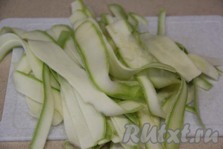 Кабачок вымыть и нарезать с помощью овощечистки на длинные и тонкие полоски.