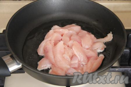 В сковороду влить масло, прогреть, выложить куриное филе, нарезанное на длинные брусочки. 