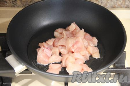 В сковороду влить масло, разогреть его и выложить куриное филе, нарезанное на средние кусочки.