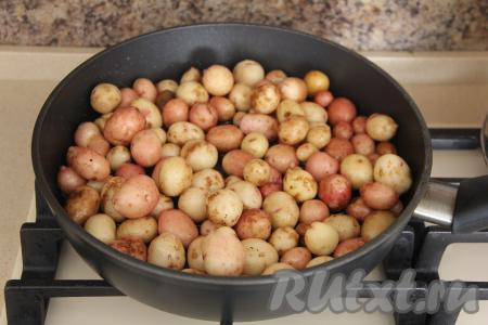 В сковороду влить масло и хорошо разогреть. Добавить подготовленную молодую картошку целиком в сковороду. Обязательно убедитесь, что картошка обсохла, лишняя жидкость при жарке не нужна.